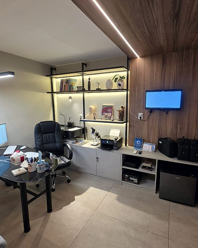 Consultório do médico, com mesa de vidro, modelos anatômicos do olho e estante iluminada